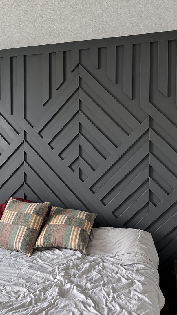 Charcoal batten wall behind the bed, a layered diamond and chevron pattern running the full width as a headboard