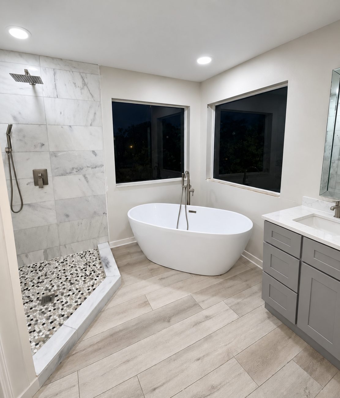 Master bathroom with marble-look tiled shower, mosaic shower pan, freestanding tub and grey quartz-top vanity