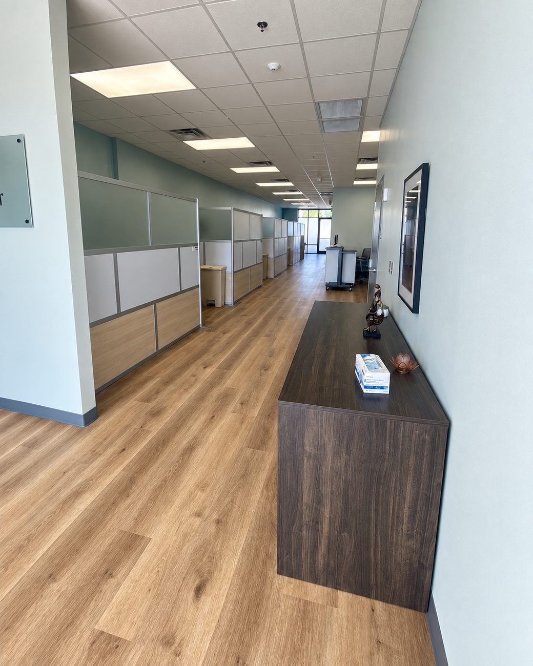 Open plan office with cubicle workstations along a corridor and plank flooring