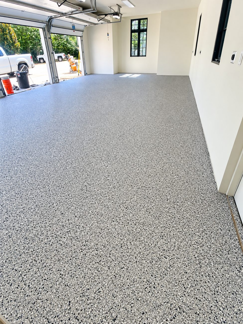Grey and black flake epoxy garage floor with equipment by the open door