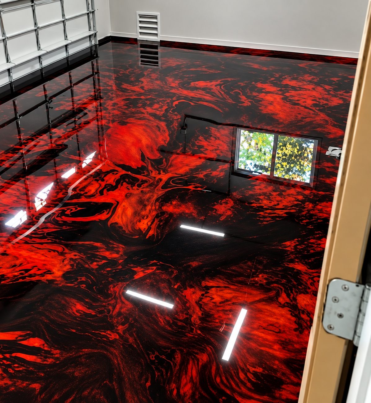 High-gloss red and black metallic epoxy floor in a garage with wire shelving