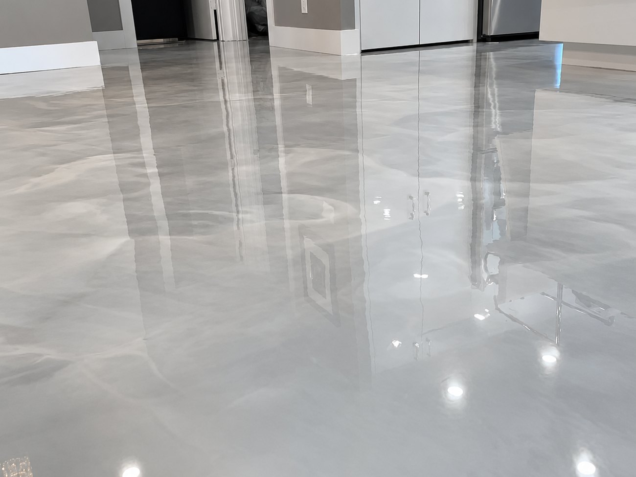 Pearl grey metallic epoxy floor running seamlessly through an open-plan living area and kitchen