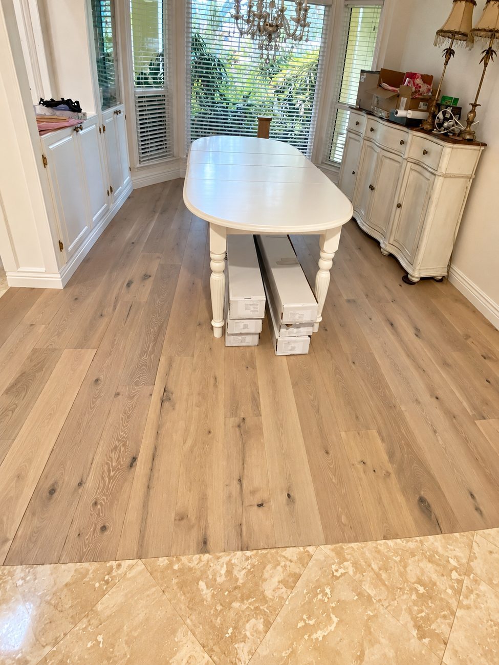 Wide plank white oak hardwood meeting an existing travertine tile floor