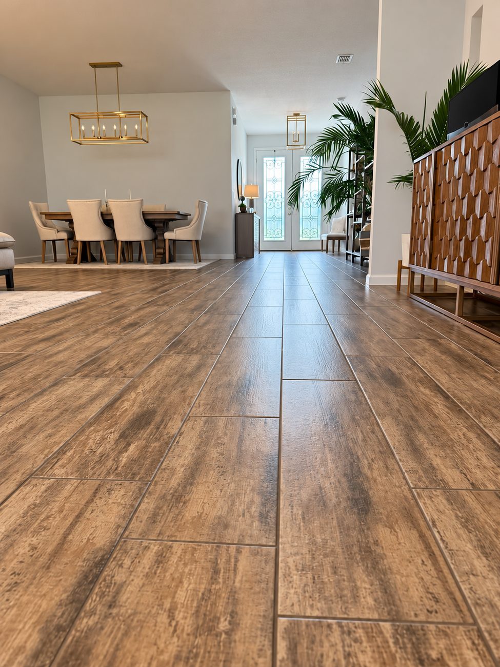Large format wood-look porcelain plank tile through an open entry and dining area