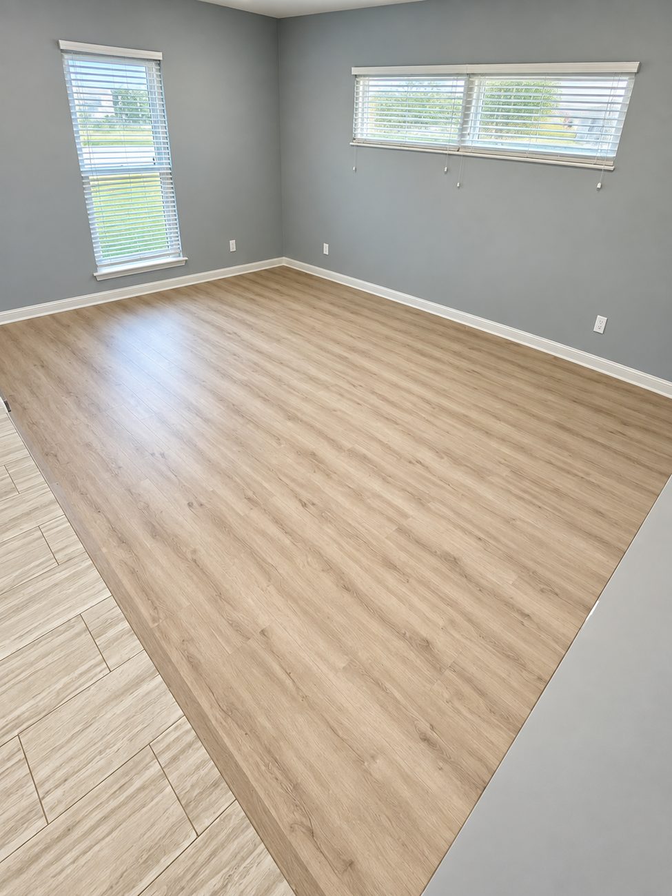 Light oak plank flooring in a bedroom, meeting the tile floor on a straight transition line