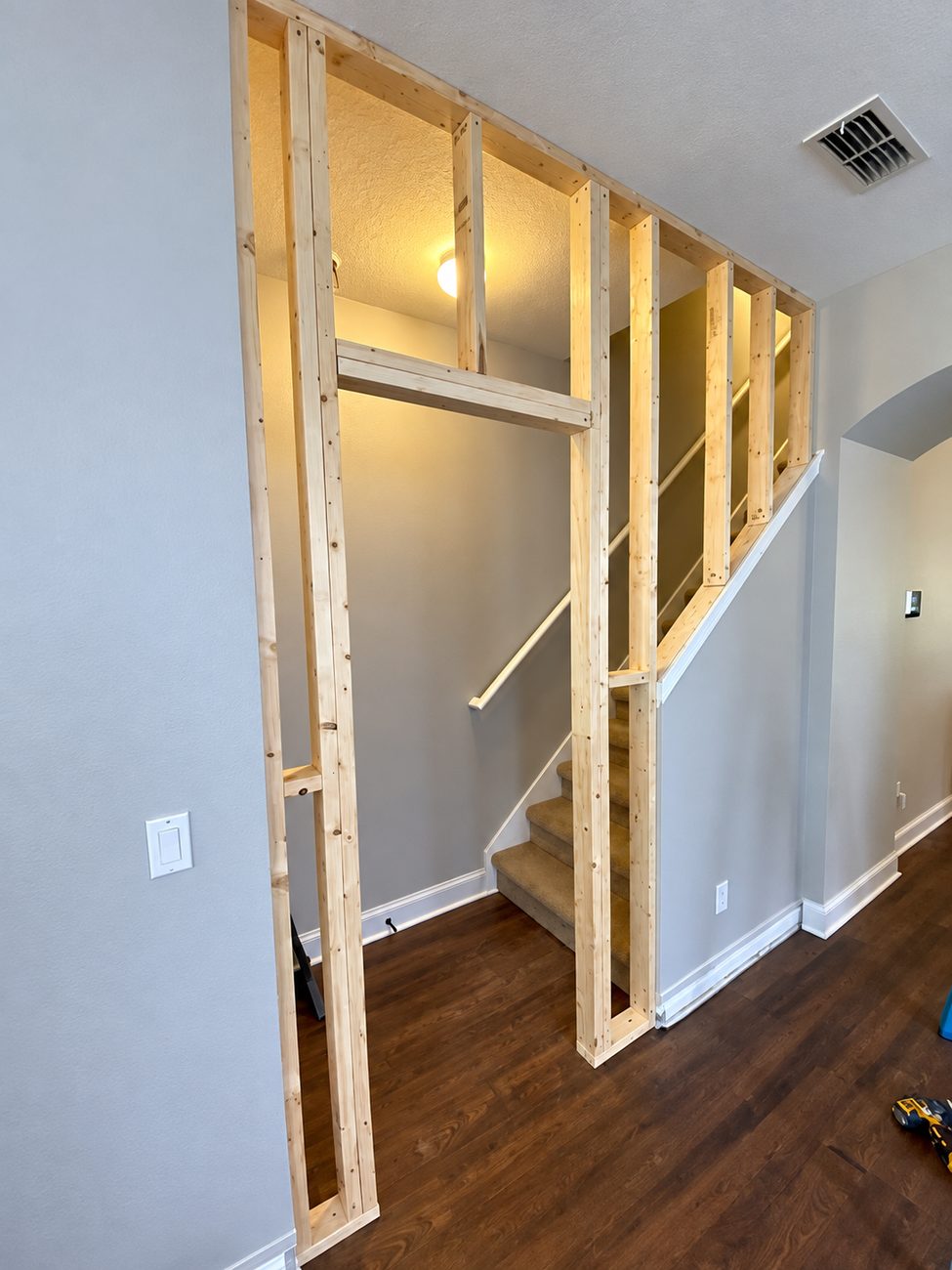New timber stud wall framed to enclose an open staircase, with a header over the door opening