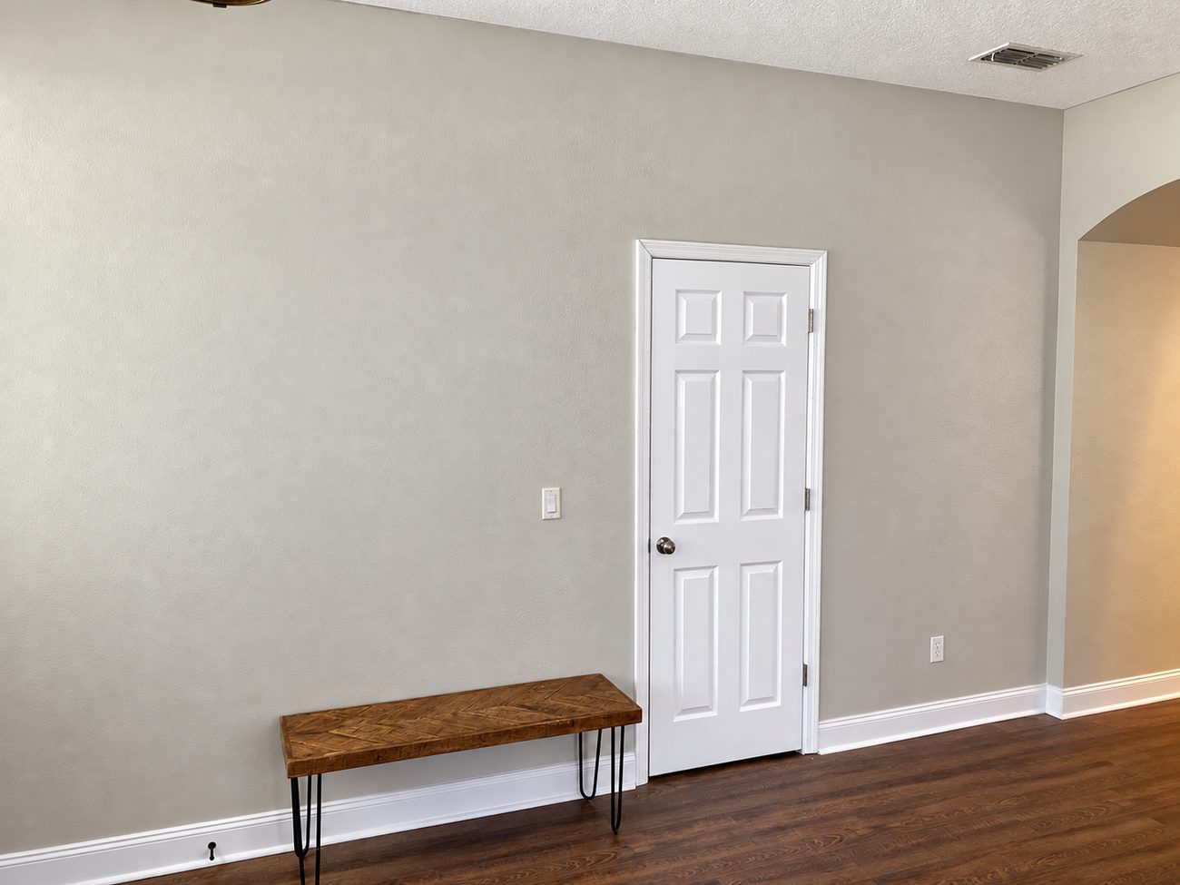 Completed painted wall with white six-panel door, baseboard and trim