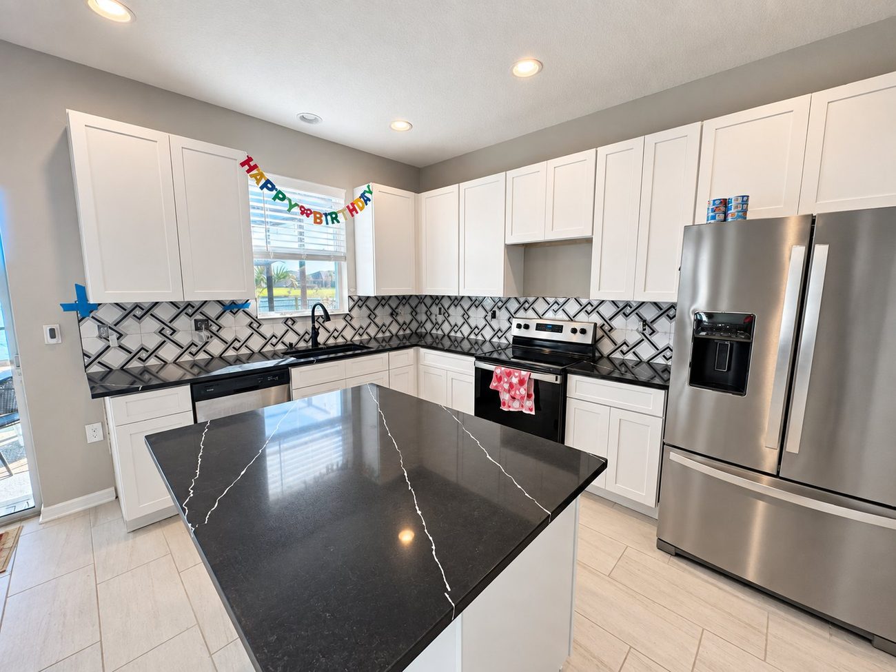 Kitchen with bold black and white geometric tile backsplash and black quartz island