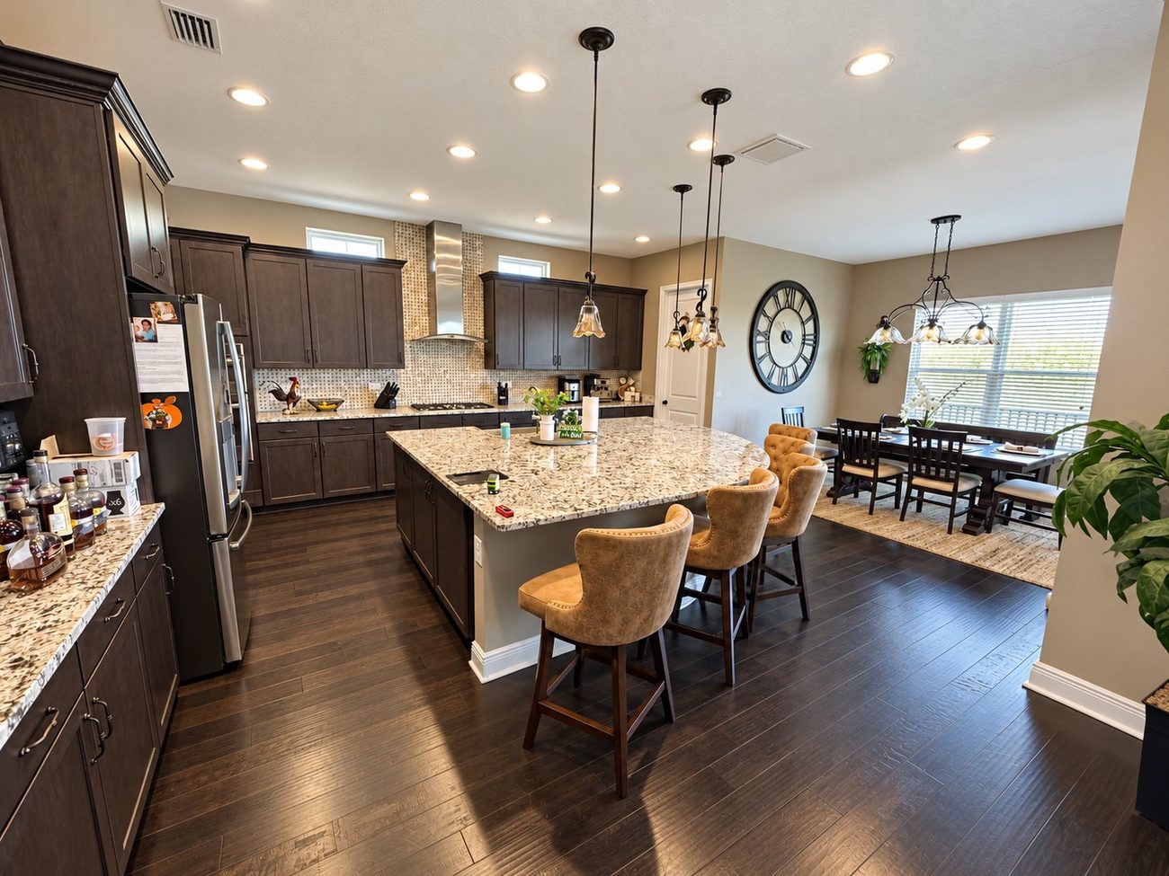 Open-plan kitchen with espresso cabinets, granite island with bar seating and adjoining dining area