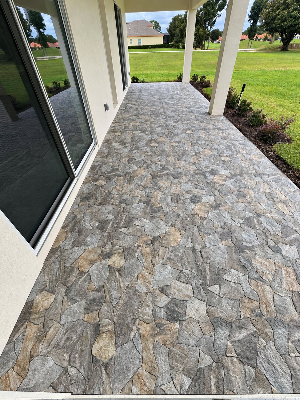 Grey and tan flagstone paving running the length of a covered rear porch beside sliding glass doors